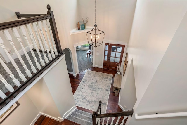 foyer with a towering ceiling, stairway, baseboards, dark wood-style floors, and a chandelier