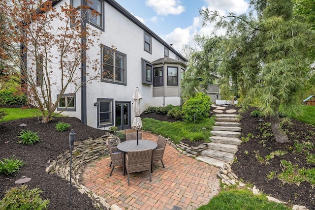 back of property featuring a patio, outdoor dining area, and stucco siding