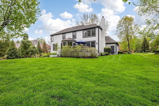 back of house with a lawn, a chimney, and stucco siding