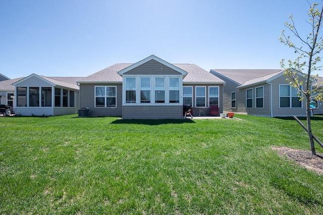 rear view of property with a sunroom, central AC unit, a lawn, and roof with shingles
