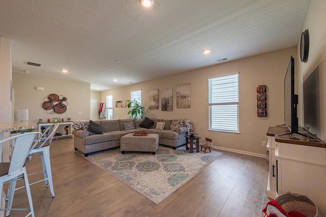 living area with recessed lighting, baseboards, light wood-type flooring, and visible vents