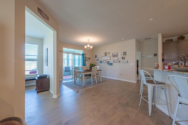 dining room featuring an inviting chandelier, baseboards, visible vents, and light wood-type flooring