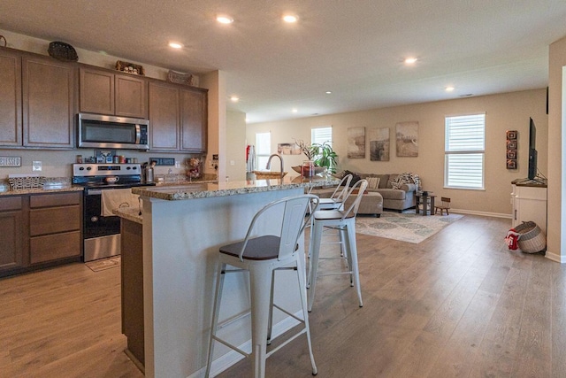 kitchen with stainless steel appliances, open floor plan, recessed lighting, and a kitchen breakfast bar