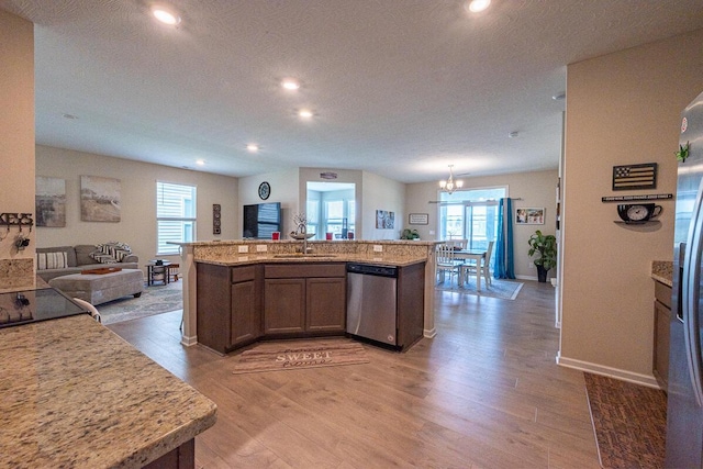 kitchen with a sink, dishwasher, light wood-style flooring, recessed lighting, and open floor plan