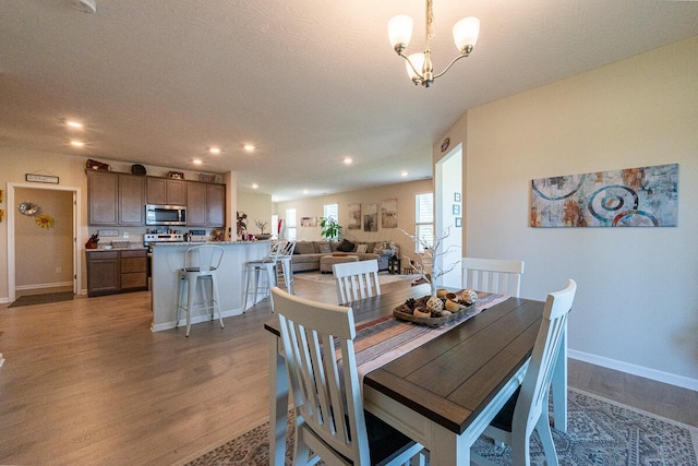 dining space featuring recessed lighting, baseboards, an inviting chandelier, and wood finished floors