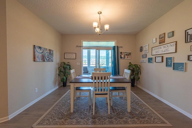 dining room featuring a textured ceiling, baseboards, an inviting chandelier, and wood finished floors