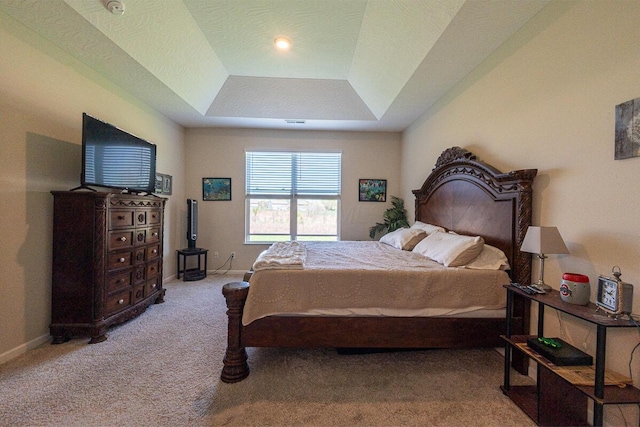 bedroom with baseboards, carpet flooring, and a tray ceiling