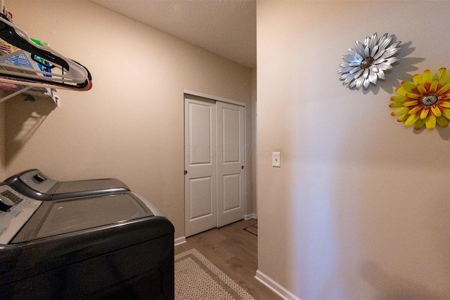 laundry area with baseboards, laundry area, washer and clothes dryer, and wood finished floors