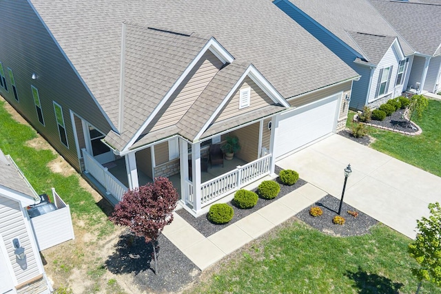 view of front of property featuring a porch, an attached garage, roof with shingles, and concrete driveway