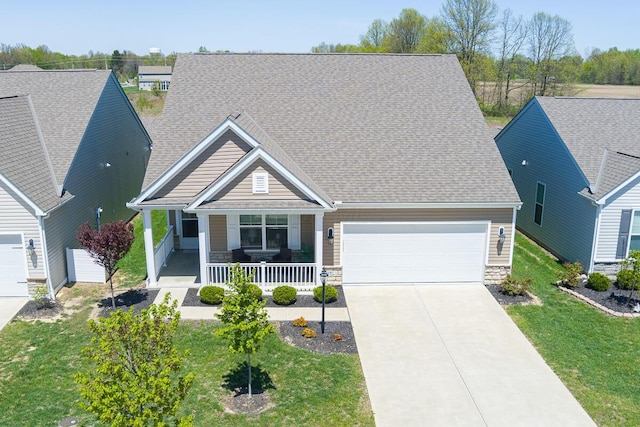 view of front of property featuring a garage, covered porch, driveway, and stone siding