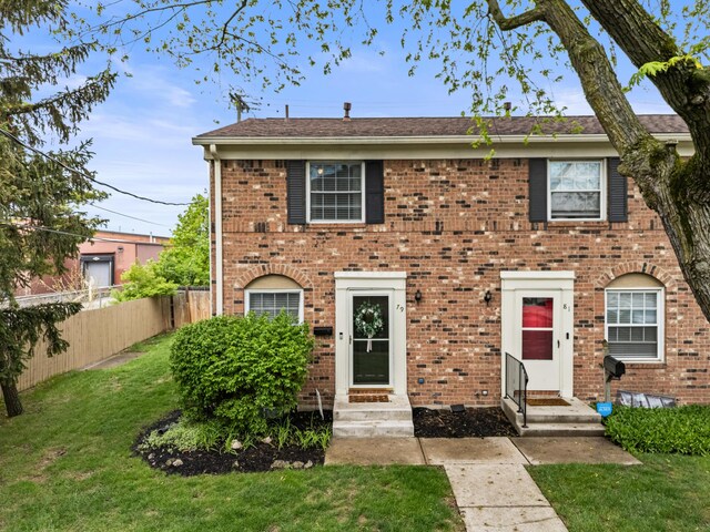 view of front of property with brick siding, fence, entry steps, and a front lawn