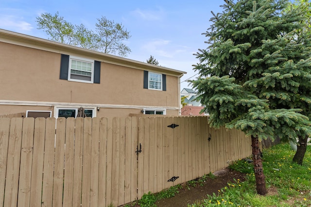 view of home's exterior with stucco siding and fence