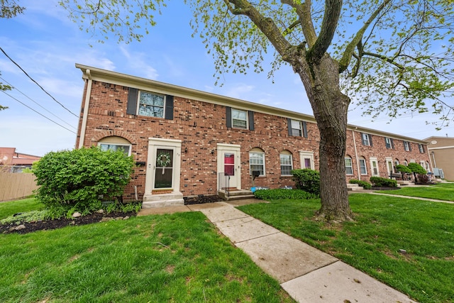 view of front facade featuring brick siding, fence, a front yard, and entry steps