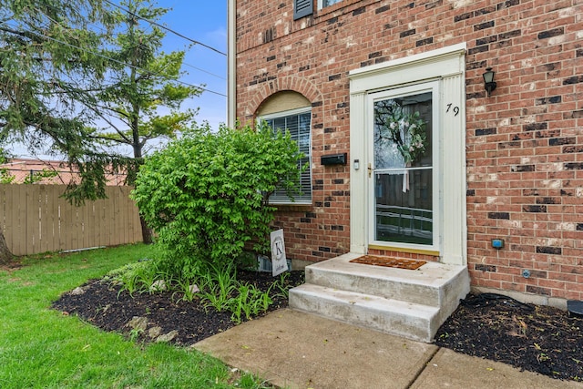 entrance to property with brick siding and fence