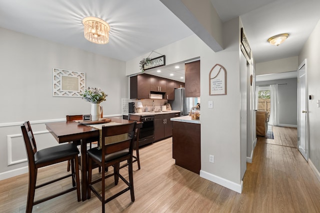dining area with baseboards, a chandelier, and light wood-style floors