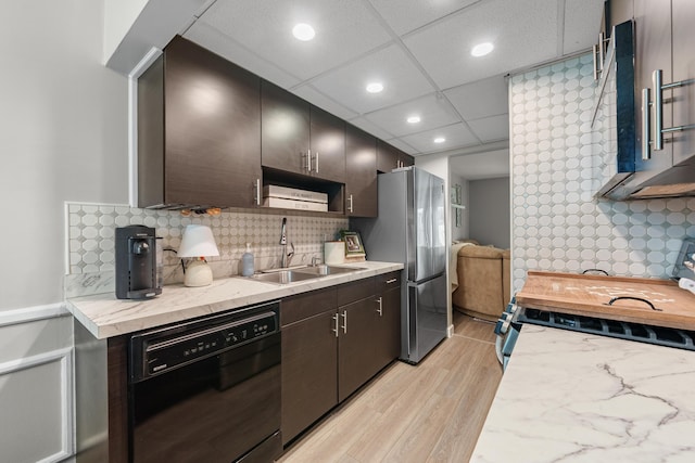 kitchen featuring dishwasher, a sink, freestanding refrigerator, light wood-style floors, and recessed lighting