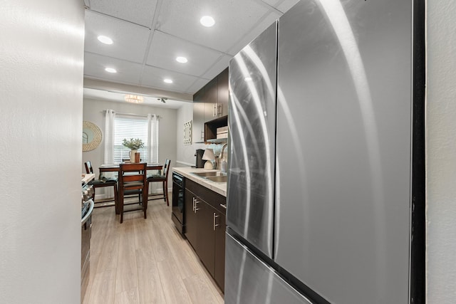 kitchen with freestanding refrigerator, recessed lighting, light countertops, a sink, and light wood finished floors