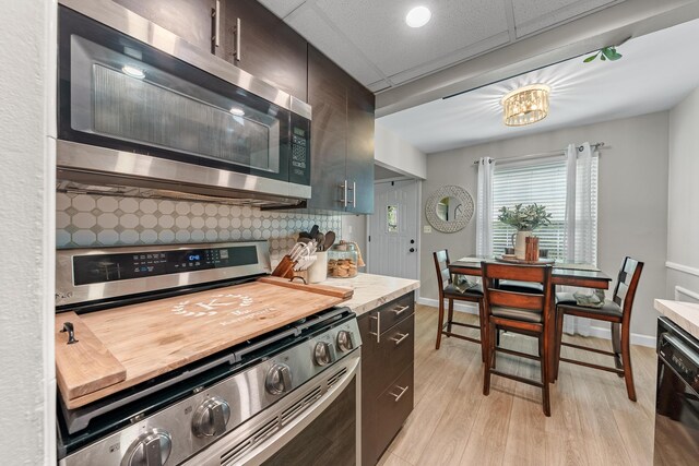 kitchen with light wood-style floors, baseboards, light countertops, tasteful backsplash, and stainless steel appliances