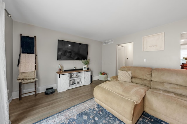 living area with baseboards, wood finished floors, and visible vents