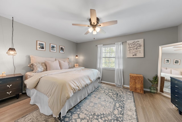 bedroom with a ceiling fan, baseboards, and light wood-style floors