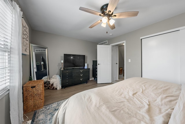 bedroom featuring a closet, a ceiling fan, wood finished floors, and visible vents