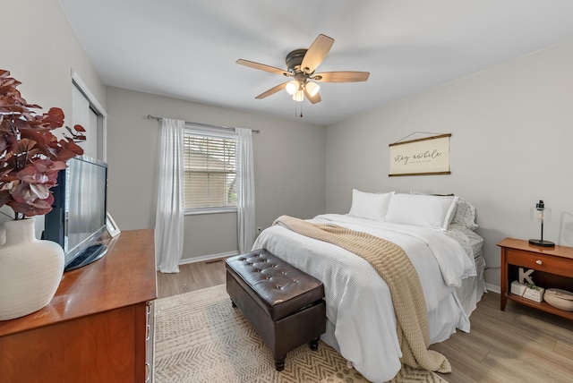 bedroom with light wood-style floors, baseboards, ceiling fan, and a closet