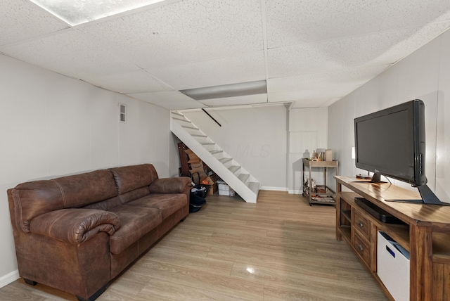 living area featuring visible vents, light wood-type flooring, stairs, and a paneled ceiling