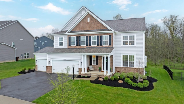 traditional-style house featuring a porch, brick siding, driveway, and a front yard