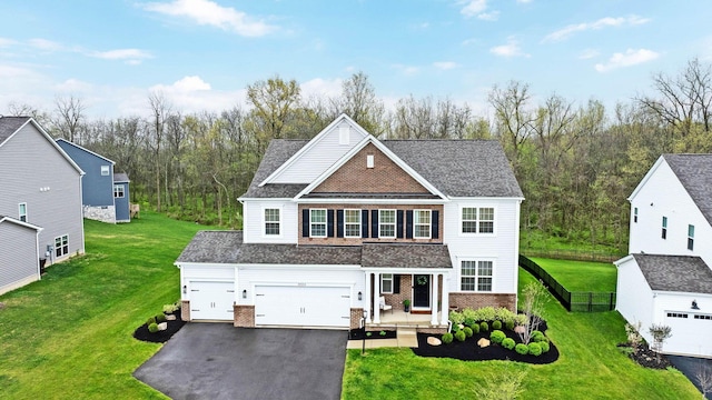 traditional-style house with fence, brick siding, a front yard, covered porch, and driveway