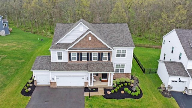 traditional-style home with brick siding, a front lawn, aphalt driveway, and a wooded view