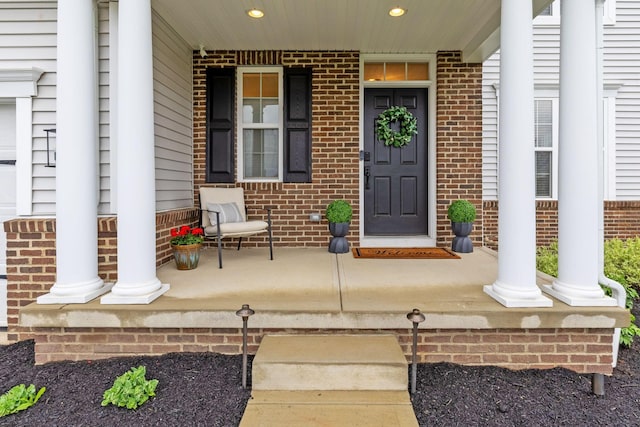 doorway to property with a porch and brick siding