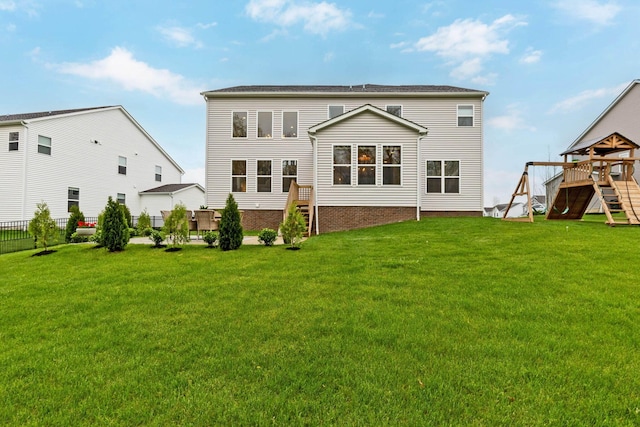 rear view of house with a playground, fence, and a lawn