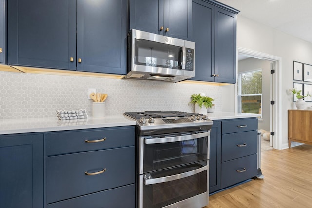 kitchen featuring light countertops, light wood-type flooring, stainless steel appliances, and blue cabinetry