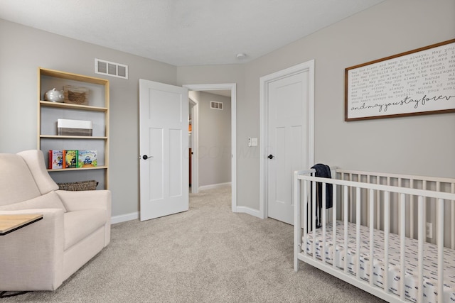 carpeted bedroom with a crib, baseboards, and visible vents