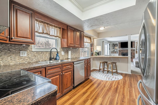 kitchen with dark countertops, appliances with stainless steel finishes, a sink, decorative backsplash, and ornamental molding