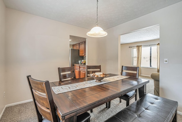 dining room featuring baseboards, carpet flooring, and a textured ceiling