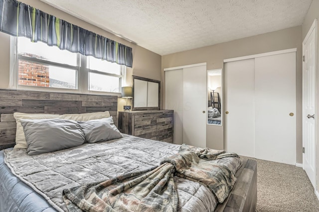 bedroom with carpet flooring, a textured ceiling, and two closets