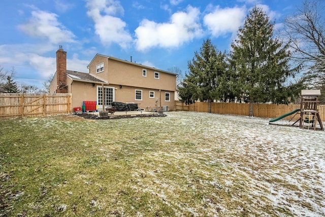 back of property with a fenced backyard, stucco siding, a chimney, a patio area, and a playground