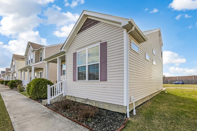 view of property exterior with a lawn and fence