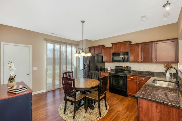 kitchen featuring dark wood-style floors, decorative backsplash, a sink, and black appliances