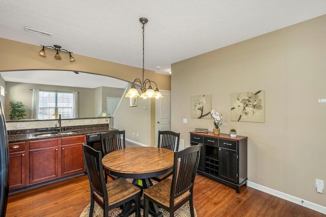 dining room featuring visible vents, baseboards, wood finished floors, and a notable chandelier