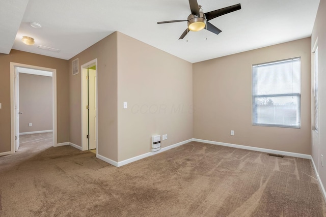 carpeted empty room with visible vents, a ceiling fan, and baseboards