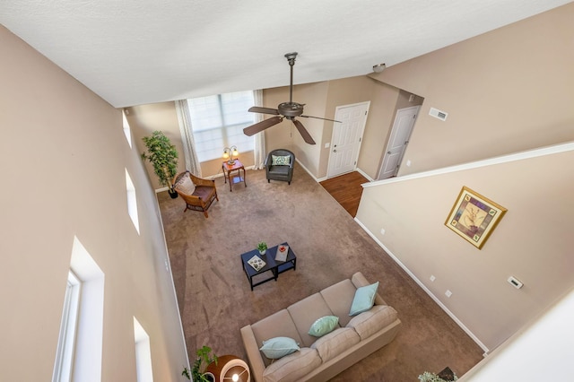 carpeted living area with baseboards and a ceiling fan