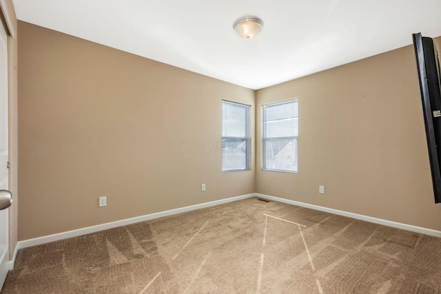 spare room with light colored carpet and baseboards