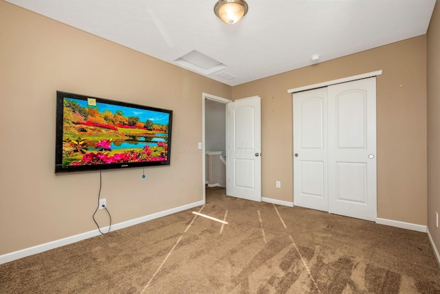 unfurnished bedroom featuring a closet, baseboards, carpet, and attic access