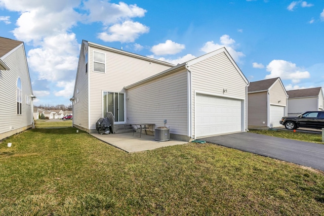 rear view of property with a yard, an attached garage, driveway, and entry steps
