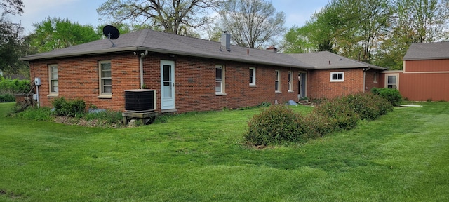 back of house featuring a lawn, central AC unit, and brick siding