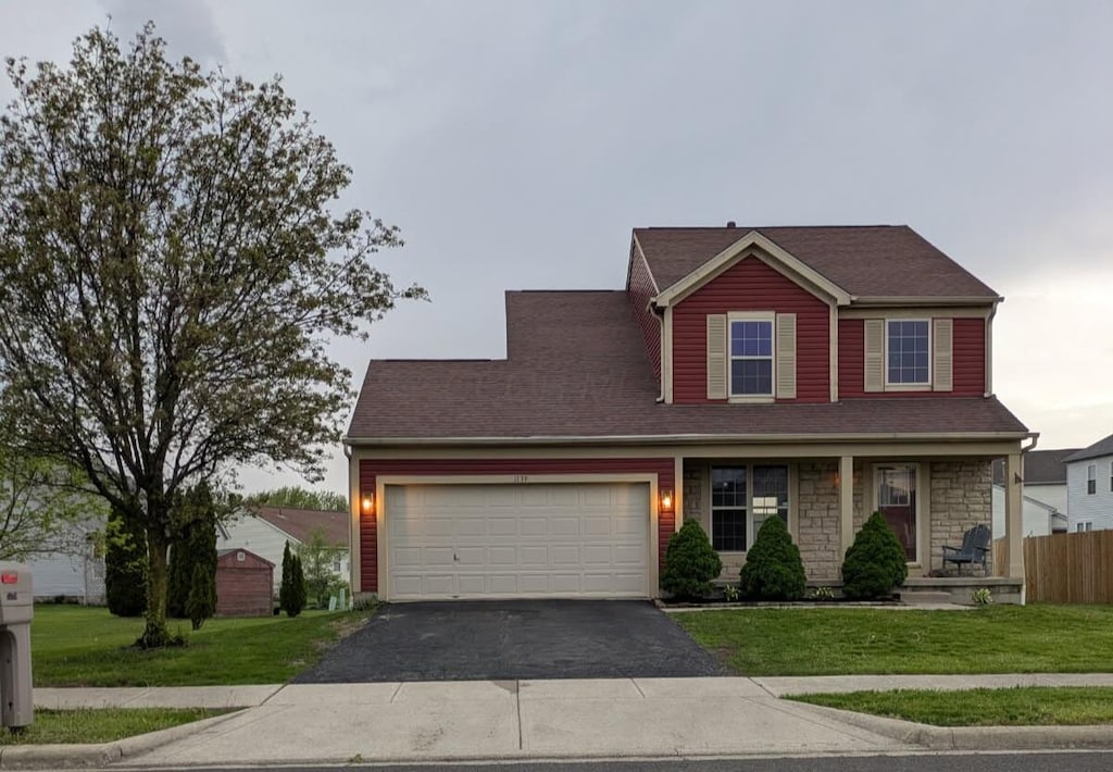 view of front of house featuring a garage, a front lawn, aphalt driveway, and covered porch