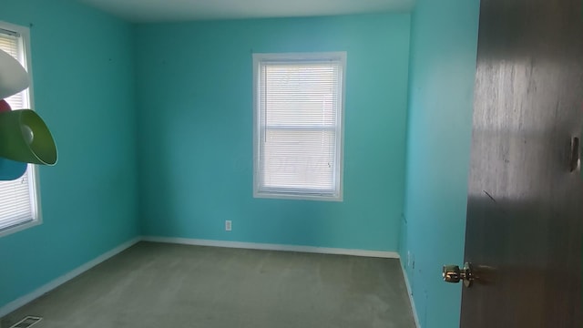 carpeted empty room featuring baseboards and visible vents