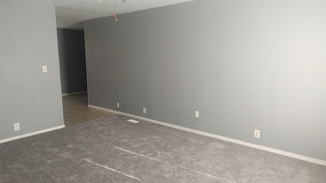 carpeted spare room featuring baseboards and a ceiling fan